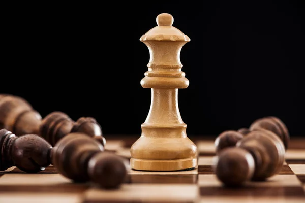 Close-up de tabuleiro de xadrez com figuras de madeira espalhadas e rainha isolada em preto — Fotografia de Stock