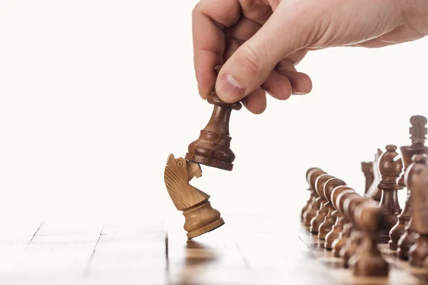 Partial view of man holding pawn near knight on wooden chessboard isolated on white — Stock Photo