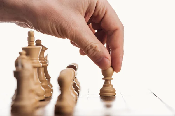 Cropped view of man doing move with beige pawn on wooden chessboard isolated on white — Stock Photo