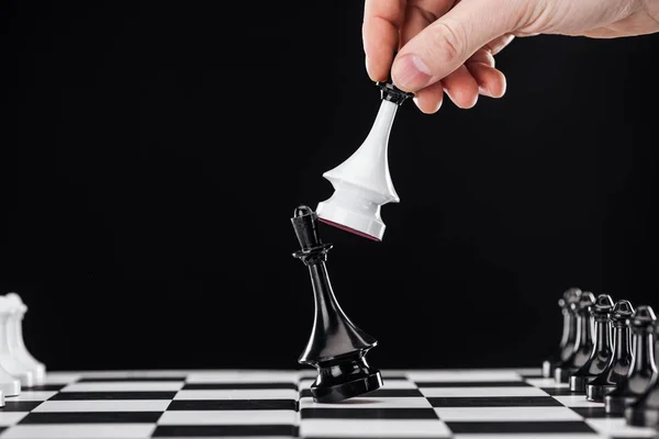 Cropped view of man doing move with queen on chessboard isolated on black — Stock Photo