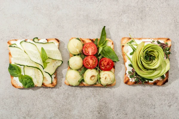 Top view of toasts with cut vegetables on textured surface — Stock Photo