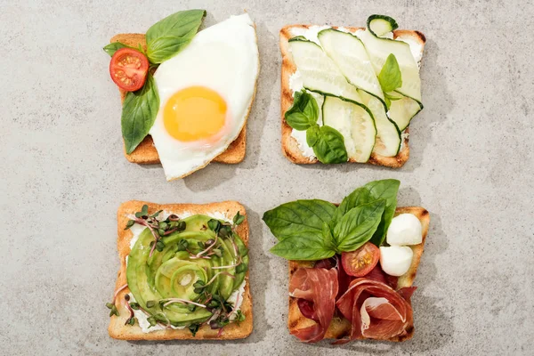 Top view of toasts with vegetables, fried egg and prosciutto on textured surface — Stock Photo