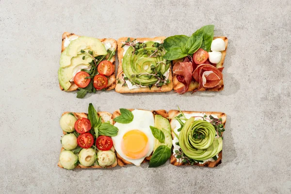 Top view of toasts with vegetables, fried egg and prosciutto on textured surface — Stock Photo
