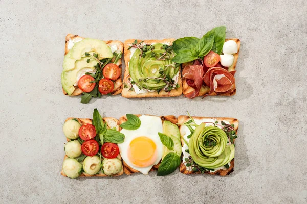 Vista superior de tostadas con verduras, huevo frito y jamón sobre superficie texturizada - foto de stock