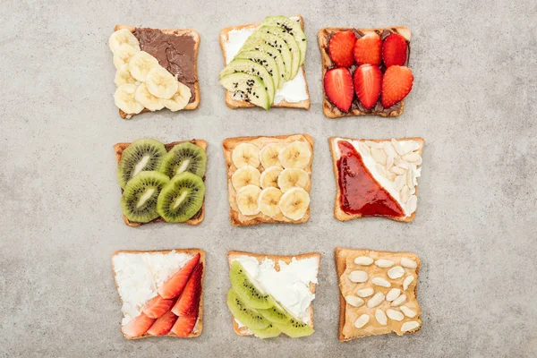 Vista dall'alto dei toast con frutta tagliata, bacche e arachidi sulla superficie testurizzata — Foto stock
