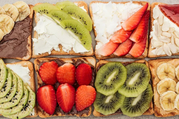 Vista superior de tostadas con frutas cortadas, fresas y cacahuetes - foto de stock