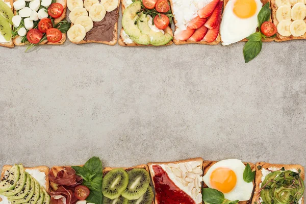 Draufsicht auf Toastbrot mit Spiegeleiern, geschnittenem Gemüse und Obst auf strukturierter Oberfläche — Stockfoto