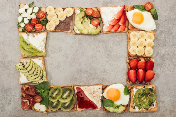 Vista dall'alto di pane tostato con uova fritte, verdure tagliate e frutta su superficie strutturata — Foto stock