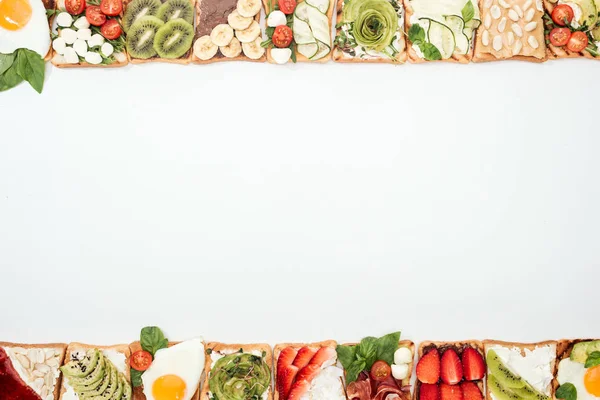 Vista dall'alto di pani tostati con frutta tagliata, verdure e arachidi su bianco — Foto stock