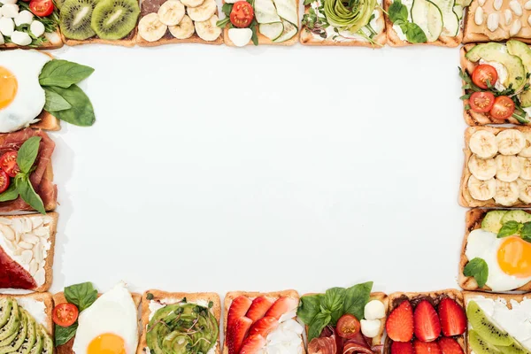 Vista dall'alto di pani tostati con frutta tagliata, verdure e arachidi su bianco — Foto stock