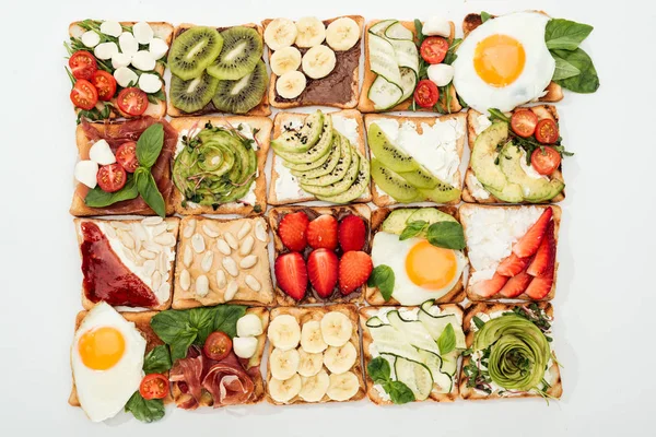 Vista dall'alto di pani tostati con frutta tagliata, verdure e arachidi su bianco — Foto stock