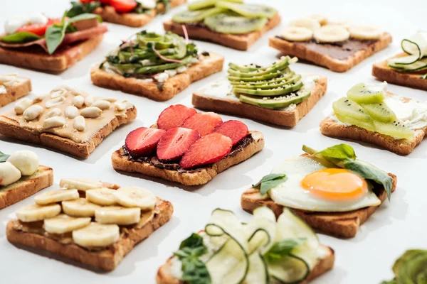 Toasts with cut fruits, fried egg and peanuts on white — Stock Photo