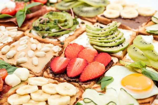 Toasts with cut fruits, strawberry. fried egg and peanuts — Stock Photo