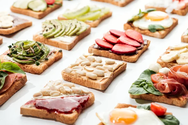 Toasts with cut fruits, fried eggs and peanuts on white — Stock Photo