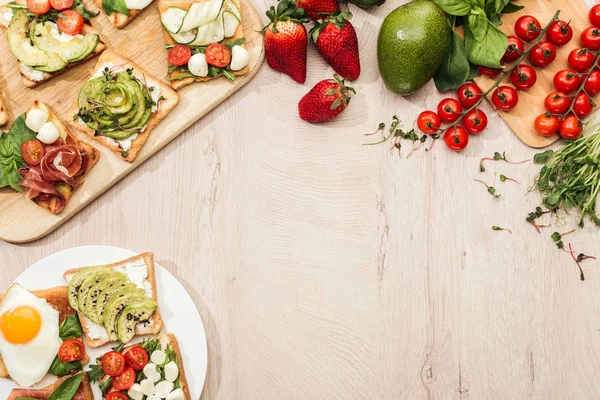 Vista superior de tostadas con verduras y jamón, vegetación e ingredientes en mesa de madera con espacio para copiar - foto de stock