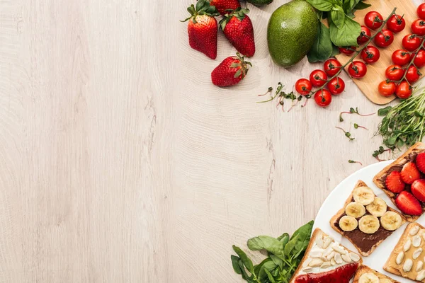 Vista superior de torradas com frutas no prato e ingredientes em mesa de madeira com espaço de cópia — Fotografia de Stock