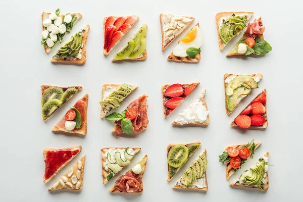 Top view of delicious toasts with fruits and vegetables isolated on white — Stock Photo