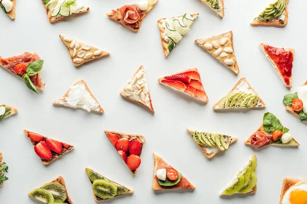 Vista superior de deliciosas torradas com frutas frescas, legumes e amendoins isolados em branco — Fotografia de Stock