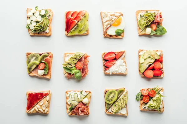 Vista dall'alto di gustosi toast con frutta, verdura e basilico isolati su bianco — Foto stock