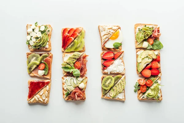 Top view of tasty toasts with fruits, vegetables and basil isolated on white — Stock Photo