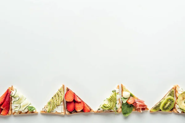 Vue de dessus des toasts aux fraises, avocat, kiwi et prosciutto isolés sur blanc avec espace de copie — Photo de stock