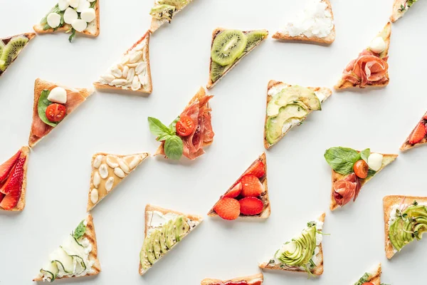 Draufsicht auf leckere Toasts mit Obst, Gemüse und Prosciutto isoliert auf weiß — Stockfoto