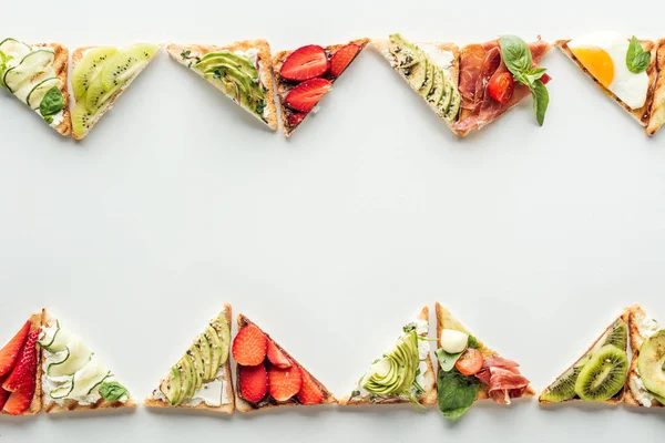 Top view of toasts with fresh fruits and vegetables isolated on white with copy space — Stock Photo