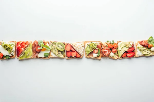 Vista dall'alto di fila di pane tostato con frutta e verdura isolata su bianco con spazio copia — Foto stock