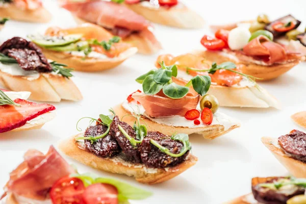 Focus selettivo della bruschetta italiana con pomodori secchi, prosciutto ed erbe su bianco — Foto stock