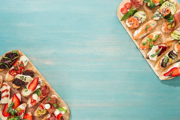 Top view of italian bruschetta with prosciutto, salmon and herbs on chopping boards with copy space — Stock Photo