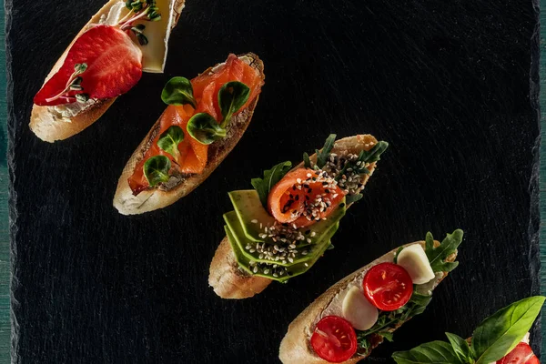 Vista dall'alto della bruschetta italiana con salmone, pomodori e avocado sul tavolo di legno — Foto stock