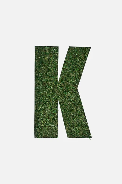 Draufsicht des ausgeschnittenen k-Buchstaben auf grünem Gras Hintergrund isoliert auf weißem Hintergrund — Stockfoto