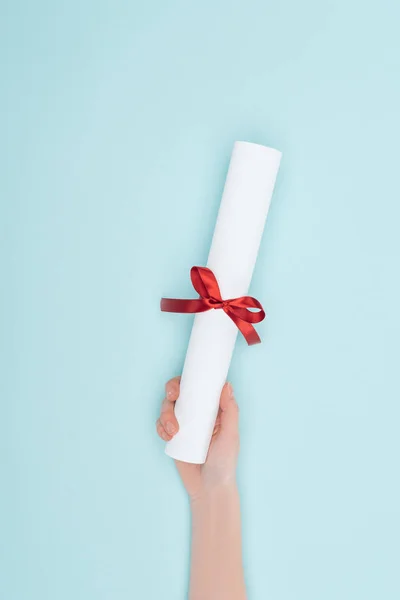 Cropped view of woman holding diploma with ribbon on blue surface — Stock Photo