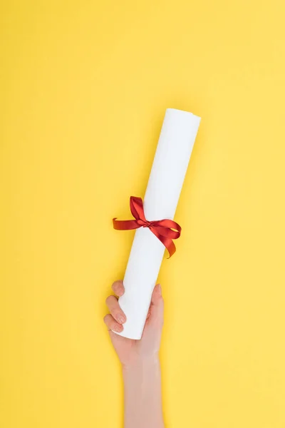 Vue recadrée de la femme titulaire d'un diplôme avec ruban sur la surface jaune — Photo de stock