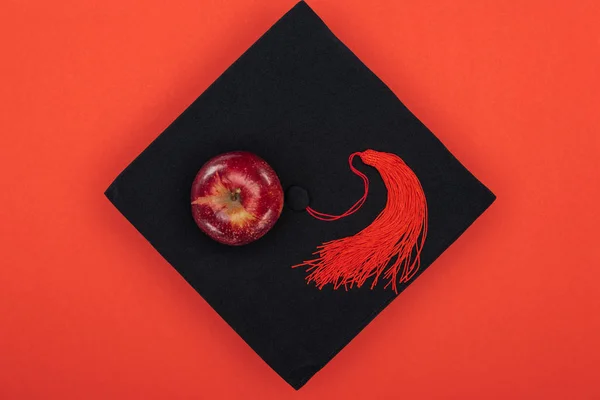 Top view of academic cap and apple isolated on red — Stock Photo