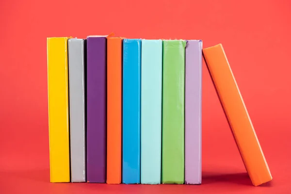 Colorful books with bright hardcovers on red surface — Stock Photo