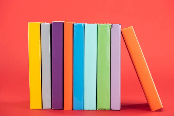 Libri colorati con copertine rigide luminose sulla superficie rossa — Foto stock