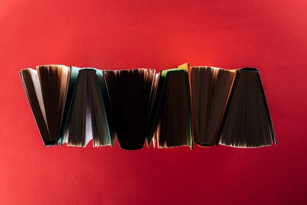 Вид сверху книг в твердой обложке на красной поверхности — стоковое фото