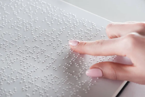 Partial view of young woman reading braille text on white paper — Stock Photo