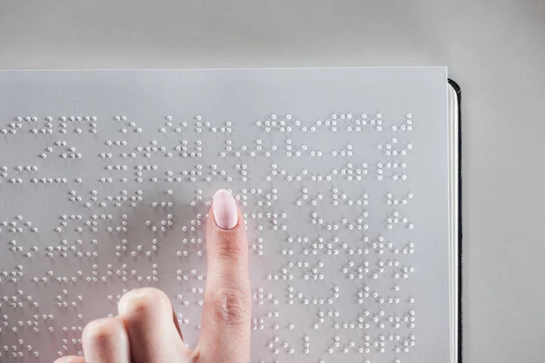 Vista superior de niña leyendo texto braille en papel blanco aislado en gris con espacio de copia - foto de stock