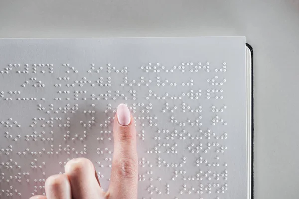 Ansicht von oben: Mädchen lesen Brailleschrift-Text auf weißem Papier isoliert auf grau mit Kopierraum — Stockfoto