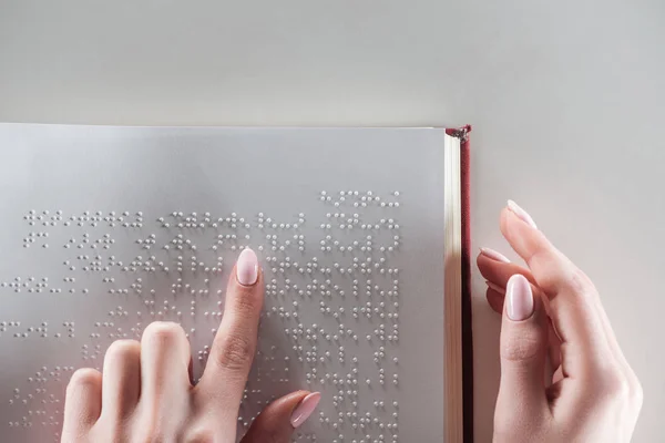 Top view of young woman reading braille text on white paper — Stock Photo