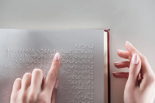 Top view of young woman reading braille text on white paper — Stock Photo