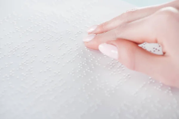 Close up view of young woman reading braille text on white paper — Stock Photo