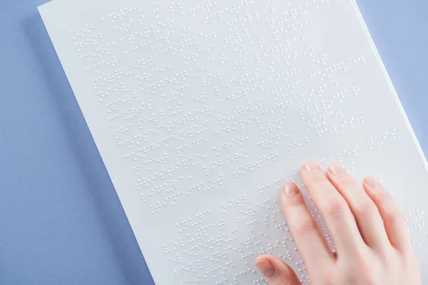 Cropped view of young woman reading braille text with hand isolated on violet with copy space — Stock Photo