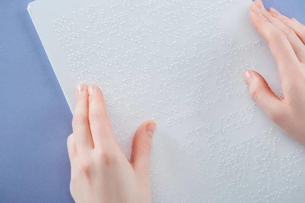 Vista cortada de menina lendo texto braille com a mão isolada em violeta — Fotografia de Stock