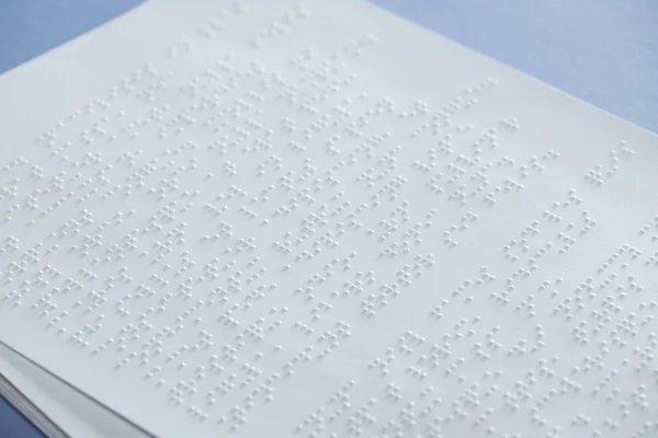 Text in international braille code on white paper isolated on violet — Stock Photo