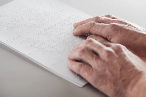 Visão cortada do homem sênior lendo texto braille isolado em cinza — Fotografia de Stock