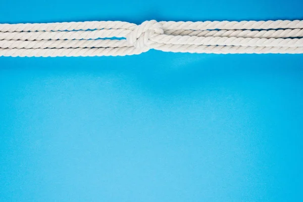 Nautical white ropes with sailor knot on blue — Stock Photo