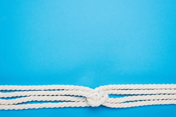 Nautical white ropes with sailor knot isolated on blue — Stock Photo